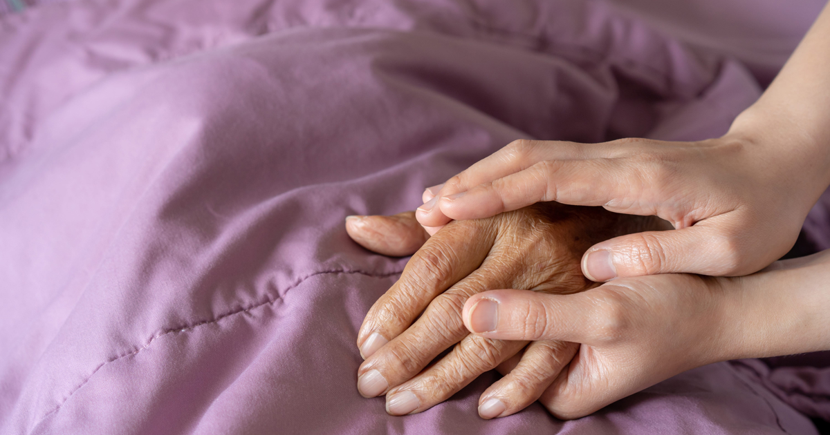 Hands resting on a table against a purple background, illustrating the EWN article on the assisted dying case