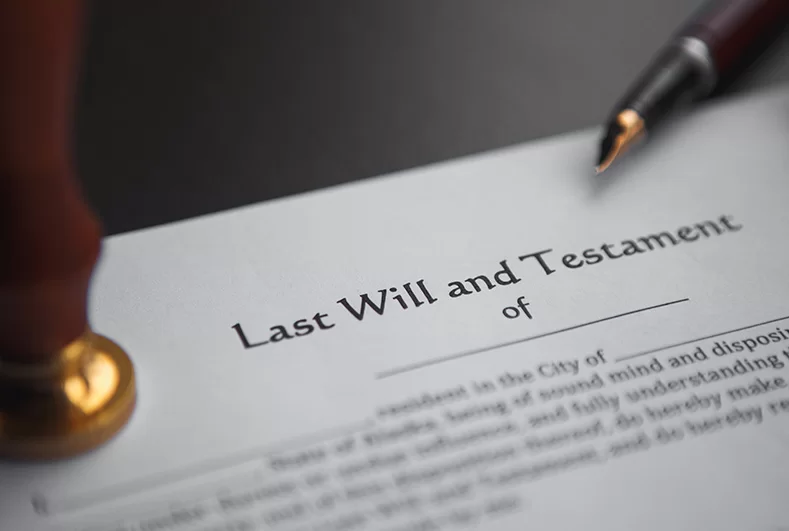 A Last Will and Testament document beside a fountain pen and a wax seal stamp
