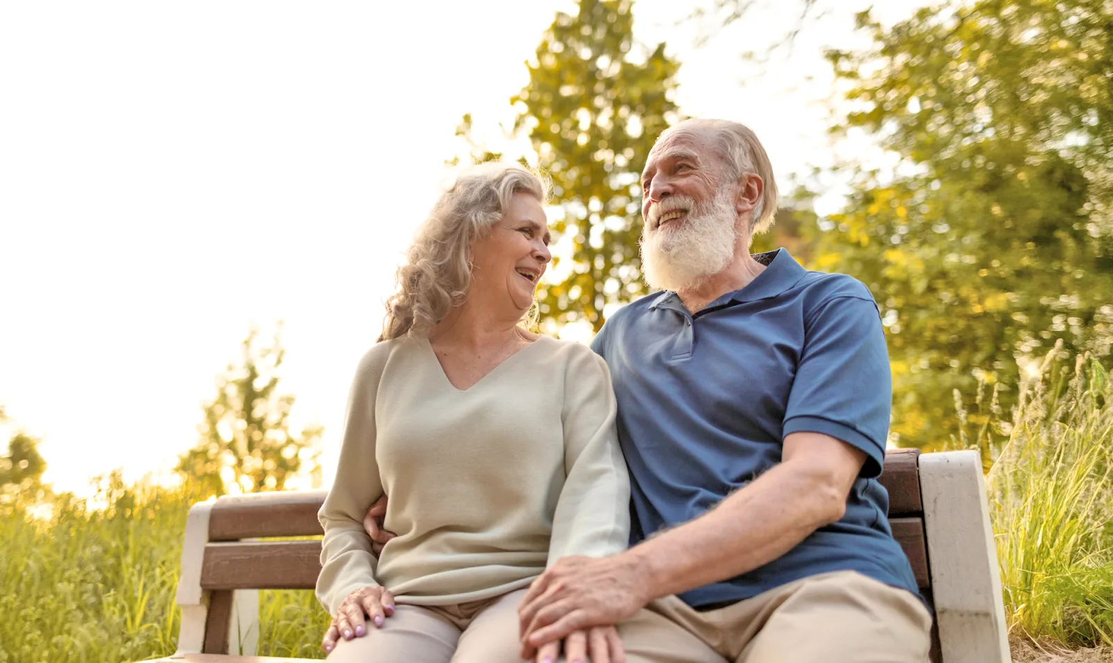 An elderly couple sitting together on a bench.